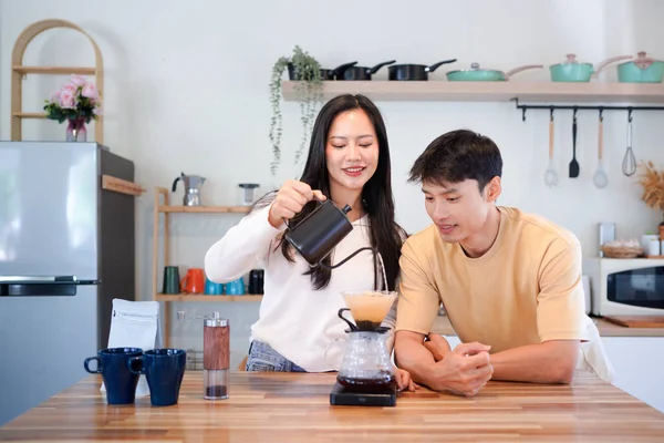 Genç aşık çift, modern mutfakta kahve damlatıcısının üzerinde kahve yaparken hafta sonu sabahlarını birlikte geçiriyorlar..