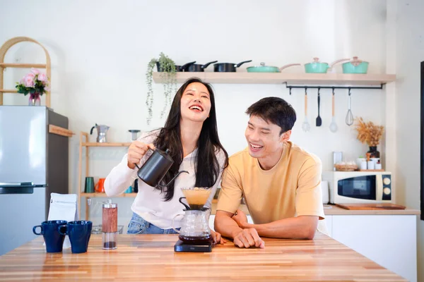 Genç aşık çift, modern mutfakta kahve damlatıcısının üzerinde kahve yaparken hafta sonu sabahlarını birlikte geçiriyorlar..