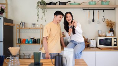 Birkaç Asyalı ya da bir çift kahve çekirdeğini öğütmeye, mutfakta kahve yapmaya ya da demlemeye. Bardak, kupa, şişe ve mutfak malzemelerini de masaya koyun. Sabah yaşam tarzı kavramı, aşk, mutluluk, aile