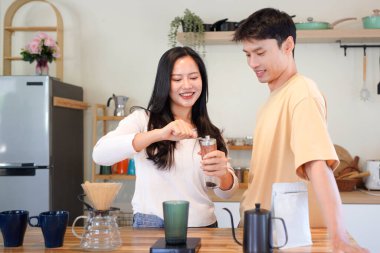 Birkaç Asyalı ya da bir çift kahve çekirdeğini öğütmeye, mutfakta kahve yapmaya ya da demlemeye. Bardak, kupa, şişe ve mutfak malzemelerini de masaya koyun. Sabah yaşam tarzı kavramı, aşk, mutluluk, aile