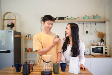 Birkaç Asyalı ya da bir çift kahve çekirdeği koklayacak, mutfakta kahve yapacak ya da demleyecek. Bardak, kupa, şişe ve mutfak malzemelerini de masaya koyun. Sabah yaşam tarzı kavramı, aşk, mutluluk, aile