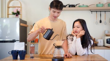 Mutlu bir çift kahvaltı için mutfakta birlikte damlatan bir kahve romantik bir sabah rutinini, kafeini ve aşkla kaynaşmayı gösteren sıcak bir ev hayatı anı..