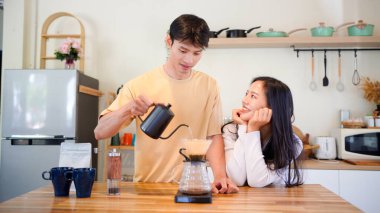 Mutlu bir çift kahvaltı için mutfakta birlikte damlatan bir kahve romantik bir sabah rutinini, kafeini ve aşkla kaynaşmayı gösteren sıcak bir ev hayatı anı..