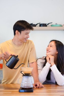 Mutlu bir çift kahvaltı için mutfakta birlikte damlatan bir kahve romantik bir sabah rutinini, kafeini ve aşkla kaynaşmayı gösteren sıcak bir ev hayatı anı..