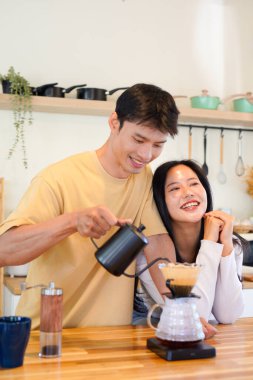 Mutlu bir çift kahvaltı için mutfakta birlikte damlatan bir kahve romantik bir sabah rutinini, kafeini ve aşkla kaynaşmayı gösteren sıcak bir ev hayatı anı..