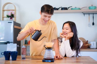 Mutlu bir çift kahvaltı için mutfakta birlikte damlatan bir kahve romantik bir sabah rutinini, kafeini ve aşkla kaynaşmayı gösteren sıcak bir ev hayatı anı..