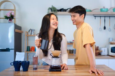 Genç aşık çift, modern mutfakta kahve damlatıcısının üzerinde kahve yaparken hafta sonu sabahlarını birlikte geçiriyorlar..