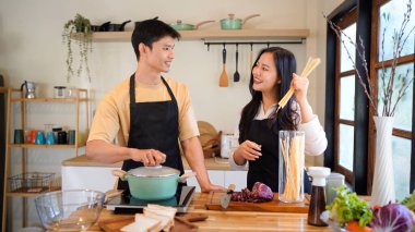 Yatay mutlu çift sıcacık bir ev mutfağında makarna pişiriyor sıcak ışık, tencere ve doğal renklerden yükselen buhar neşeli ve samimi bir atmosfer yaratıyor, yaşam tarzı için ideal..