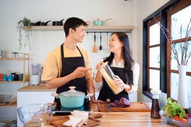 Yatay mutlu çift sıcacık bir ev mutfağında makarna pişiriyor sıcak ışık, tencere ve doğal renklerden yükselen buhar neşeli ve samimi bir atmosfer yaratıyor, yaşam tarzı için ideal..