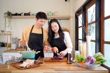 Yatay mutlu çift sıcacık bir ev mutfağında makarna pişiriyor sıcak ışık, tencere ve doğal renklerden yükselen buhar neşeli ve samimi bir atmosfer yaratıyor, yaşam tarzı için ideal..
