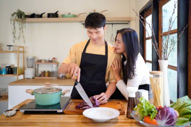 Yatay mutlu çift sıcacık bir ev mutfağında makarna pişiriyor sıcak ışık, tencere ve doğal renklerden yükselen buhar neşeli ve samimi bir atmosfer yaratıyor, yaşam tarzı için ideal..