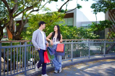 Güzel, genç bir çift alışverişte eğleniyor, birlikte eğleniyor, alışveriş yaptıktan sonra parkta duran güzel, gülümseyen genç bir çiftin portresi..