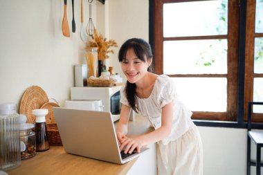 Genç iş kadını uzaktan kumandalı, serbest çalışan bir kadın sabahları mutfak tezgahında dizüstü bilgisayar kullanıyor ve kişisel gelişim üzerine çalışıyor..