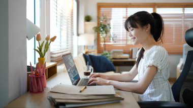Masada otururken konforlu oturma odasında dizüstü bilgisayarda çalışan kadın bir uzman. Serbest çalışan kadın sosyal ağlarda internette sohbet ediyor..