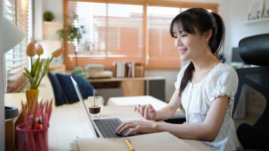 Masada otururken konforlu oturma odasında dizüstü bilgisayarda çalışan kadın bir uzman. Serbest çalışan kadın sosyal ağlarda internette sohbet ediyor..