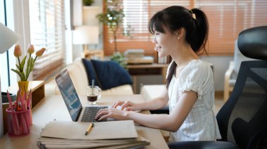 Masada otururken rahat ev oturma odasında dizüstü bilgisayarda çalışan bir kadın. Serbest çalışan kadın sosyal ağlarda internette sohbet ediyor..