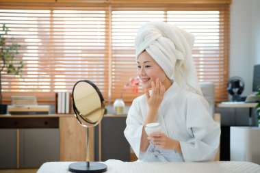 Kadınlar evde bornoz ve havlu giyer cilt bakımını gençleştirir, aynaya bakar. Günlük güzellik rutini.