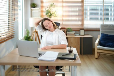 Beyaz kadın evden çalışırken kollarını uzatıyor, dizüstü bilgisayarla uzun süre çalıştıktan sonra mola veriyor..