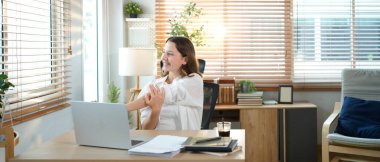 Beyaz kadın evden çalışırken kollarını uzatıyor, dizüstü bilgisayarla uzun süre çalıştıktan sonra mola veriyor..