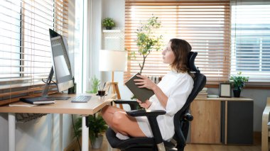 Kadın merkez ofis çalışanlarının çalışma alanı. Kadın açık güneşli odada bilgisayarla kitap okuyor. Modern tasarım.