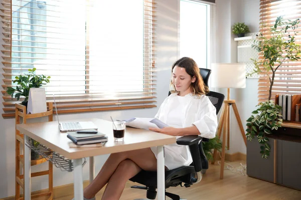 Merkez ofisteki kadın, uzaktan çalışma, fikirler ve düşünme üzerine araştırma yapmak için belgeler ve dizüstü bilgisayar. Bilgisayarlı mutlu kız, notlar yazıyor ve evde serbest ağ arayışı yapıyor..