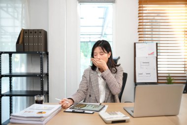 İş kadını ofis çalışanı dizüstü bilgisayarda yorgun düşmüş ağzı açık, gözleri açık gri takım elbiseli uykulu Asyalı kadın..