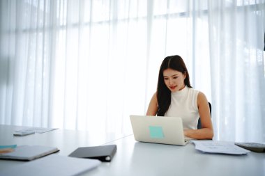 Ofiste otururken laptopuyla çalışan çekici genç bir iş kadınının portresi..