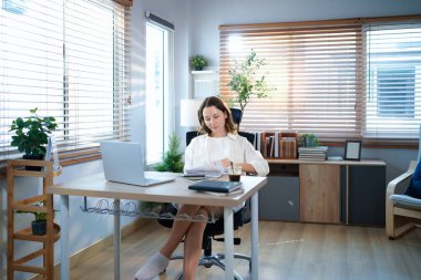 Merkez ofisteki kadın, uzaktan çalışma, fikirler ve düşünme üzerine araştırma yapmak için belgeler ve dizüstü bilgisayar. Bilgisayarlı mutlu kız, notlar yazıyor ve evde serbest ağ arayışı yapıyor..