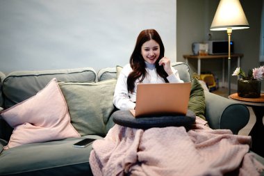 Kadın darphanede dizüstü bilgisayar, internet bağlantısı ve gülümseme kullanarak oturuyor. Kapalı alandaki mutlu kadın teknoloji eğlence aktivitesi.