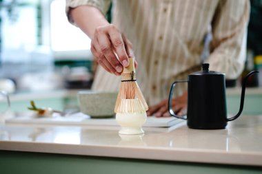Japon kibrit yeşil çayını geleneksel bambu çırpıcısıyla hazırlayan bir adamın elleri. El temizleme çırpma veya çırpma makinesine yakın plan.