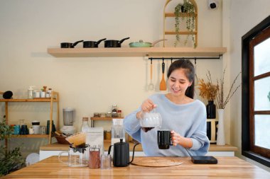 Kadın mutfakta kahve içiyor, kahvaltı yapıyor ve sabah evde dinlenmeye başlıyor. Mutlu bayan sert, sıcak ve siyah espresso fincanının keyfini çıkarıyor. Apartmanda çay ve neşe..