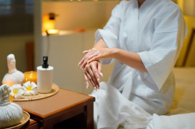 Bornozlu kadın güzellik salonundaki cilt bakım rutini sırasında gerekli yağı sürüyor. Güzellik merkezi konsepti. Vücut bakımı.