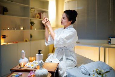 Bornozlu kadın güzellik salonundaki cilt bakım rutini sırasında gerekli yağı sürüyor. Güzellik merkezi konsepti. Vücut bakımı.