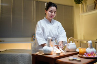 Beyaz bornozlu güzel bir kadın kaplıcada spa işlemleri yaptıktan sonra dinleniyor, çay içiyor. Zarif kadın rahatlıyor, iç huzurunu ve dengesini buluyor..