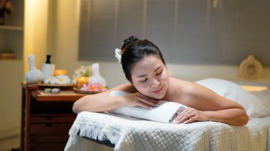 Bir sağlık merkezinde masaj masasında uzanmış, siyah saçlı, güzel bir kadın..