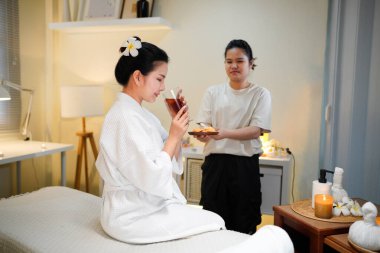 Terapist, kadın müşterilere hoş geldin içkisi sunuyor. Spa salonu resepsiyonisti, müşterilerine içecek ve içecek getiriyor..