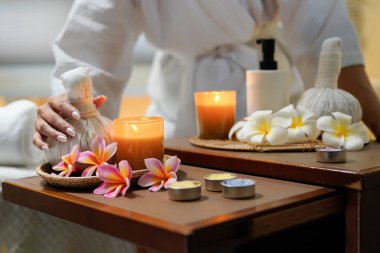 Beyaz cübbe giyen kadınların elleri dinlenme ve spa terapisi konsepti için doğal bir bitkisel kompres tutuyorlar..