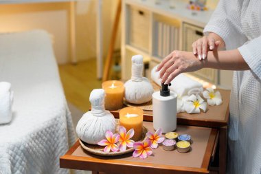 Bornozlu kadın güzellik salonundaki cilt bakım rutini sırasında gerekli yağı sürüyor. Güzellik merkezi konsepti. Vücut bakımı.