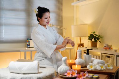 Bornozlu kadın güzellik salonundaki cilt bakım rutini sırasında gerekli yağı sürüyor. Güzellik merkezi konsepti. Vücut bakımı.