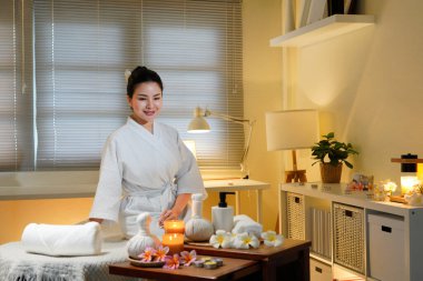 Bornozlu kadın güzellik salonunda huzur ve lüks içinde oturuyor. Spa 'da masaj masasında oturup meditasyon yapan sakin bir kadının profili. Boşluğu kopyala.