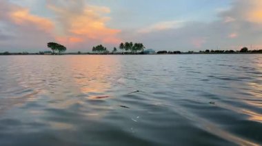 Sakin Suların Üzerinde Sakin Tropik Günbatımı, Siluetli Palmiye Ağaçları, Suyun Üzerinde Yansıyan Altın Gökyüzü