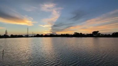 Sakince Bulut Hareketi ve Güç Hattlarıyla Sakin Suların Üzerinde Gün Batımı