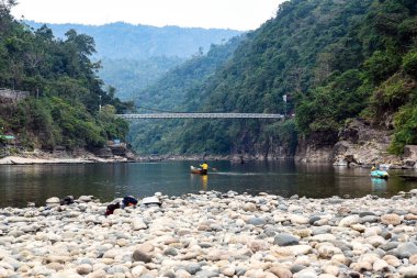 Scenic River Canyon With Rocky Shore, Forested Hills, and a Suspension Bridge Over Water
