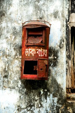 Kırık pencereli yıpranmış duvar ve harap olmuş dış binanın dış cephesinde kırmızı posta kutusu