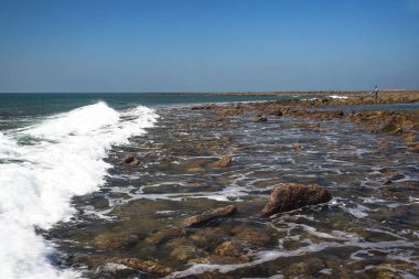 Coastal Scene with Gentle Waves, Rocks, and a Blue Horizon