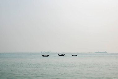 Three Wooden Boats Floating on a Calm River Under a Hazy Sky