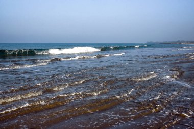 Scenic Ocean Waves Rolling Onto a Serene Shoreline Under a Clear Sky