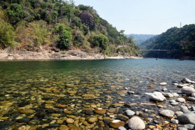 Scenic River Canyon With Rocky Shore, Forested Hills, and a Suspension Bridge Over Water