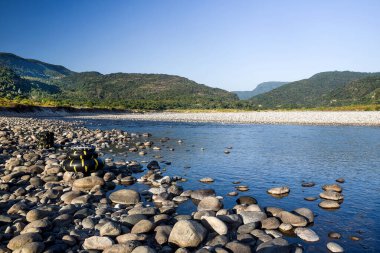 Scenic Riverbank With Pebbles and Tubes Under Clear Blue Sky