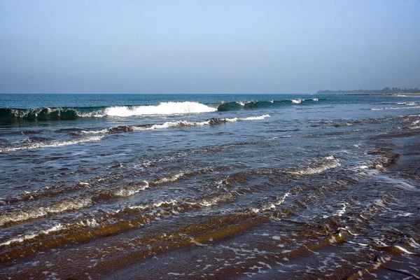 Scenic Ocean Waves Rolling Onto a Serene Shoreline Under a Clear Sky